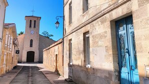 Una calle estrecha con una torre de iglesia, edificios de piedra y una puerta azul.