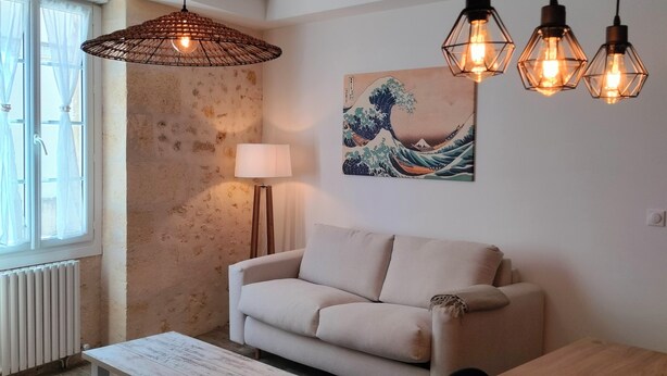 Una sala de estar moderna con un sofá, una mesa de comedor y lámparas colgantes.