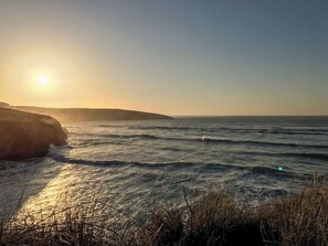 Paisaje costero con olas y un acantilado al atardecer.