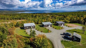 A lodge with three cabins, a gravel driveway, and a parking area with vehicles. - Lake View Cottage with Private Hot Tub - Eagle View (West Bay)