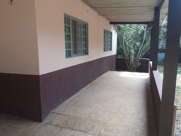 A covered outdoor area with tiled flooring and a building with a white and brown exterior.