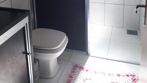 A bathroom with a toilet, a sink, and a shower area. - Casa para temporada  (Brasília)