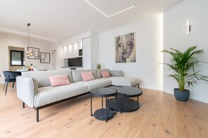 A modern living room with a sectional sofa, two round coffee tables, and a potted plant.