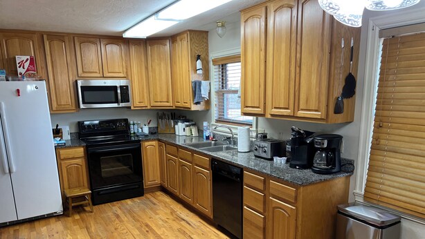 A kitchen with wooden cabinets, a stainless steel refrigerator, a microwave, an oven, a dishwasher, a coffee maker, and a trash can. - Ben Ranch House overlooking river - Full 3 Bedroom house. Minutes from Fairfax. (Ralston)