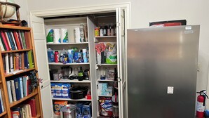 A kitchen with a refrigerator, open pantry shelves stocked with food items, a sink, and a bookshelf filled with books. - Ben Ranch House overlooking river - Full 3 Bedroom house. Minutes from Fairfax. (Ralston)