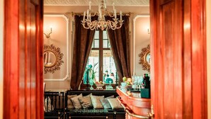 A hallway with a wooden bench, a chandelier, and a view of a room with a window and a mirror. - Pałac na Wodzie  (Podgorzyn)