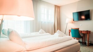 A hotel room with two beds, a desk, a chair, a TV, and a window with curtains. - Pałac na Wodzie  (Podgorzyn)