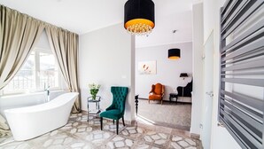 A modern bathroom with a freestanding bathtub, a green armchair, and a large window with beige curtains. - Pałac na Wodzie  (Podgorzyn)