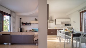 Ein modernes Wohnzimmer mit einer Couch, einem Essbereich mit Tisch und Stühlen sowie einer Küche mit Schränken und Geräten.
