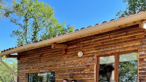 A rustic wooden cabin with a porch, two chairs, and a table. - le Charme D'une Cabane, le Confort en Plus (Aups)