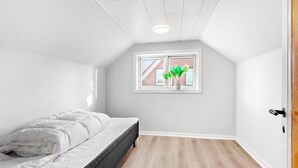 A bedroom with a bed, a window with a plant, and a wooden floor. - 2 bedroom amazing home in Sørvad (Sørvad)