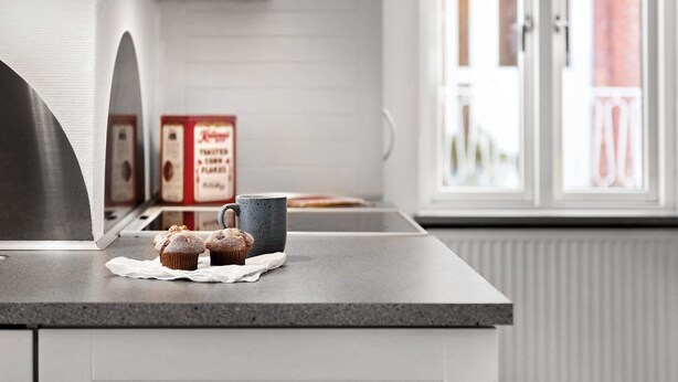 A kitchen counter with a coffee maker, a box of coffee pods, and two muffins on a napkin. - 2 bedroom amazing home in Sørvad (Sørvad)