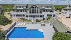 Ein großes Strandhaus mit zwei Etagen, mehreren Balkonen und einem Swimmingpool.
