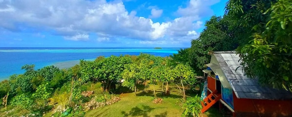 A lush garden with a view of the ocean and a small island. - LTB FENUA Farm & Camping (Raiatea)