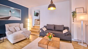 Een moderne woonkamer met een bank, een salontafel en een schilderij van een vuurtoren.