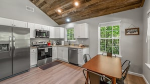 A modern kitchen with white cabinets, stainless steel appliances, and a wooden ceiling. - The Otter Box Cabin on 92 acres beside DeSoto State Park | Walking Ramp | Wi-Fi (Fort Payne)