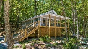 A wooden cabin with a deck and stairs, surrounded by trees. - The Otter Box Cabin on 92 acres beside DeSoto State Park | Walking Ramp | Wi-Fi (Fort Payne)
