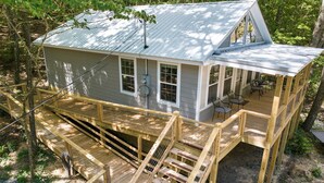 A wooden house with a metal roof, a deck, and a staircase leading to a covered porch area. - The Otter Box Cabin on 92 acres beside DeSoto State Park | Walking Ramp | Wi-Fi (Fort Payne)