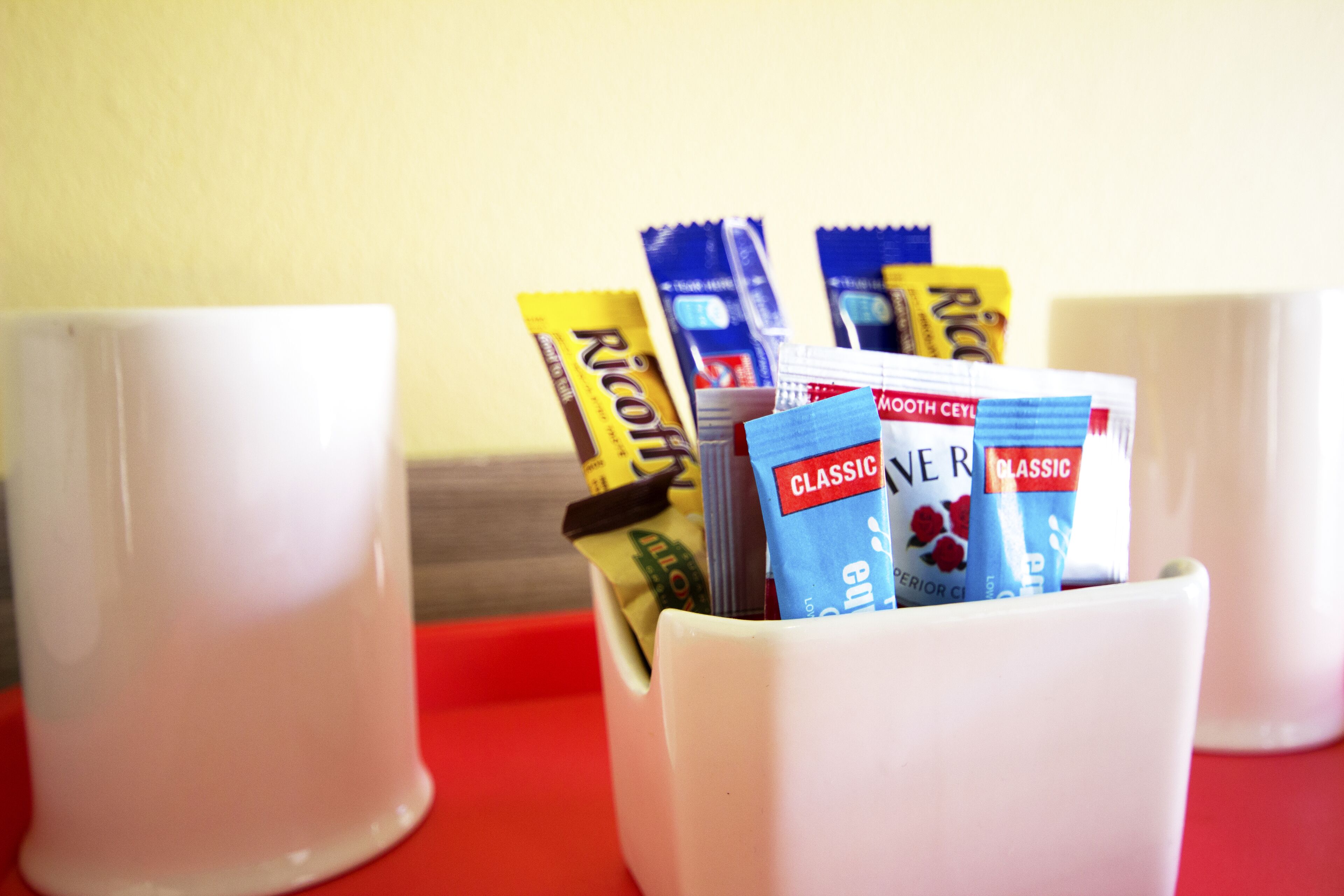Una taza blanca llena de varias barras de chocolate y un tubo de crema.