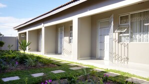 A modern building with a covered walkway, large windows, and a garden area with stepping stones. - Minilitha Lodge (Richards Bay)