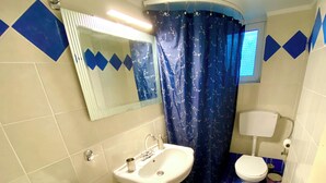 A bathroom with a white sink, a toilet, and a shower curtain.