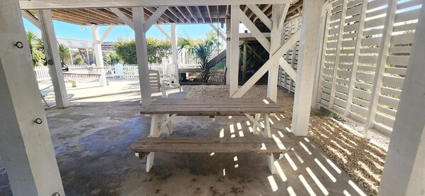 A covered outdoor area with a wooden bench and a white fence.