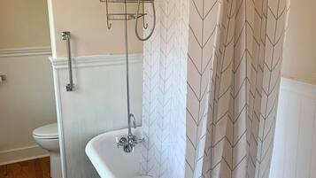 Ein Badezimmer mit freistehender Badewanne, einer Dusche mit Regendusche, einem Handtuchhalter und einer Toilette.