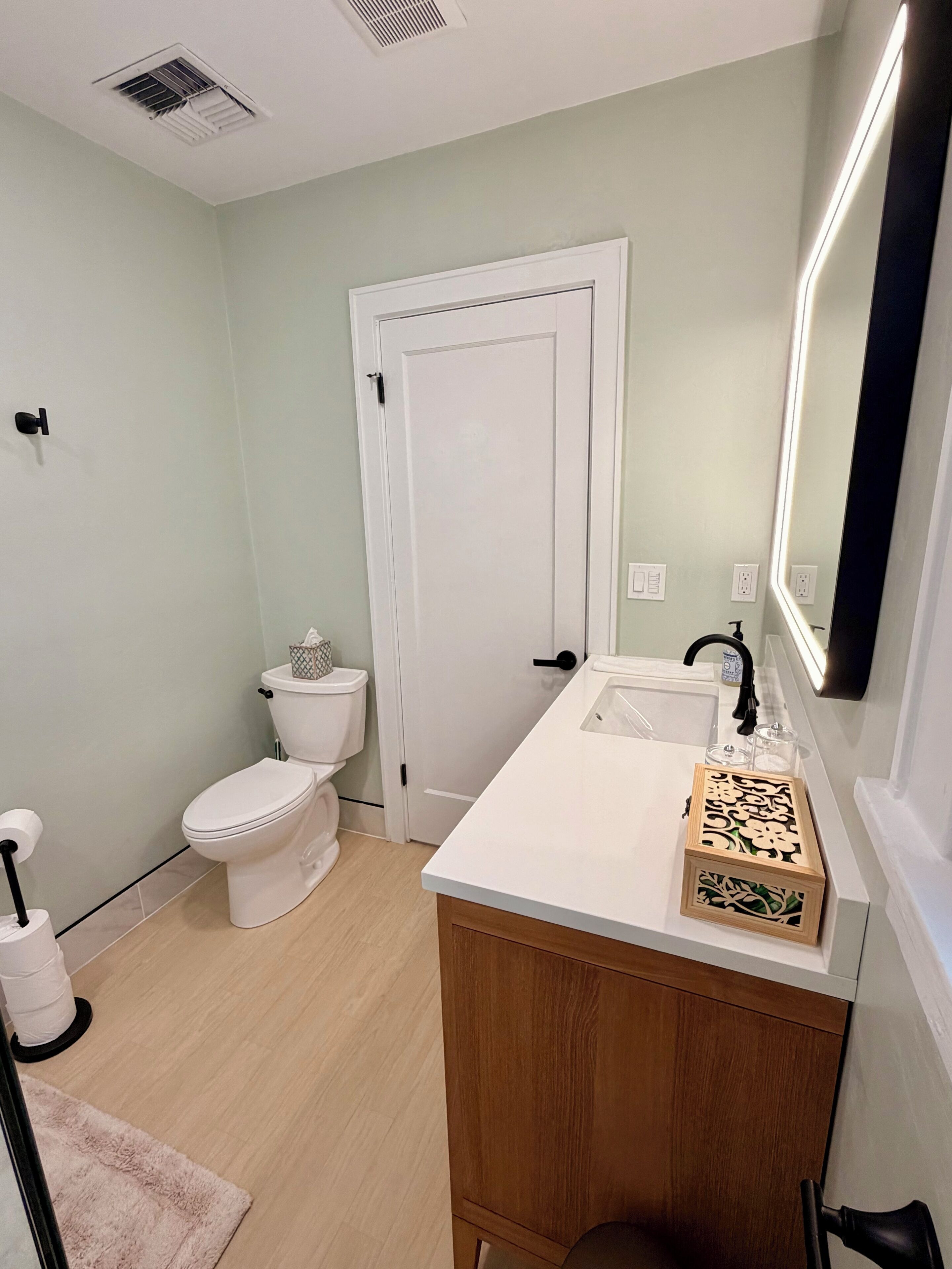 A bathroom with a toilet, sink, and mirror.