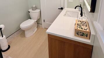 A bathroom with a toilet, sink, and mirror.