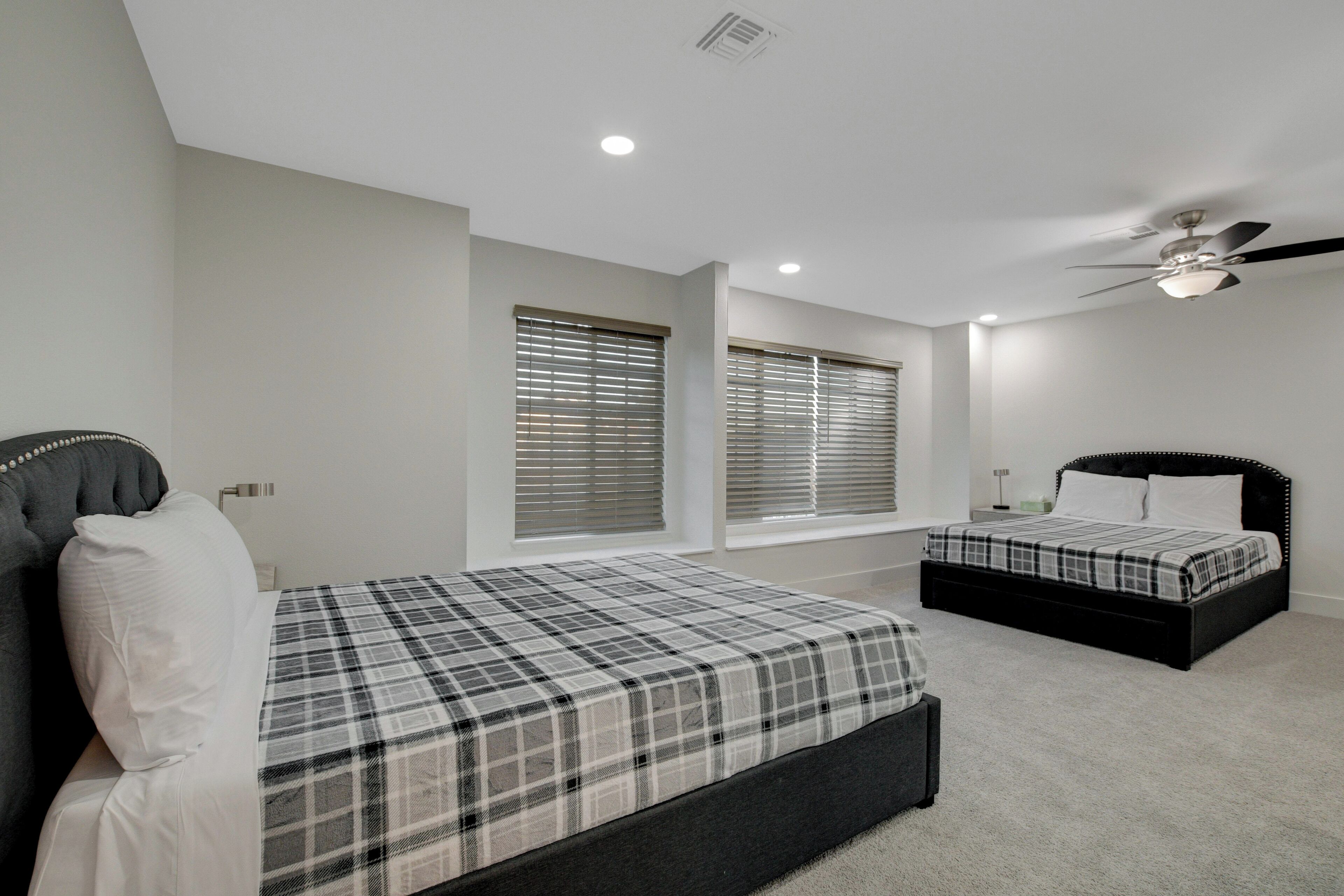 A bedroom with a bed, a window with blinds, a ceiling fan, and a nightstand.