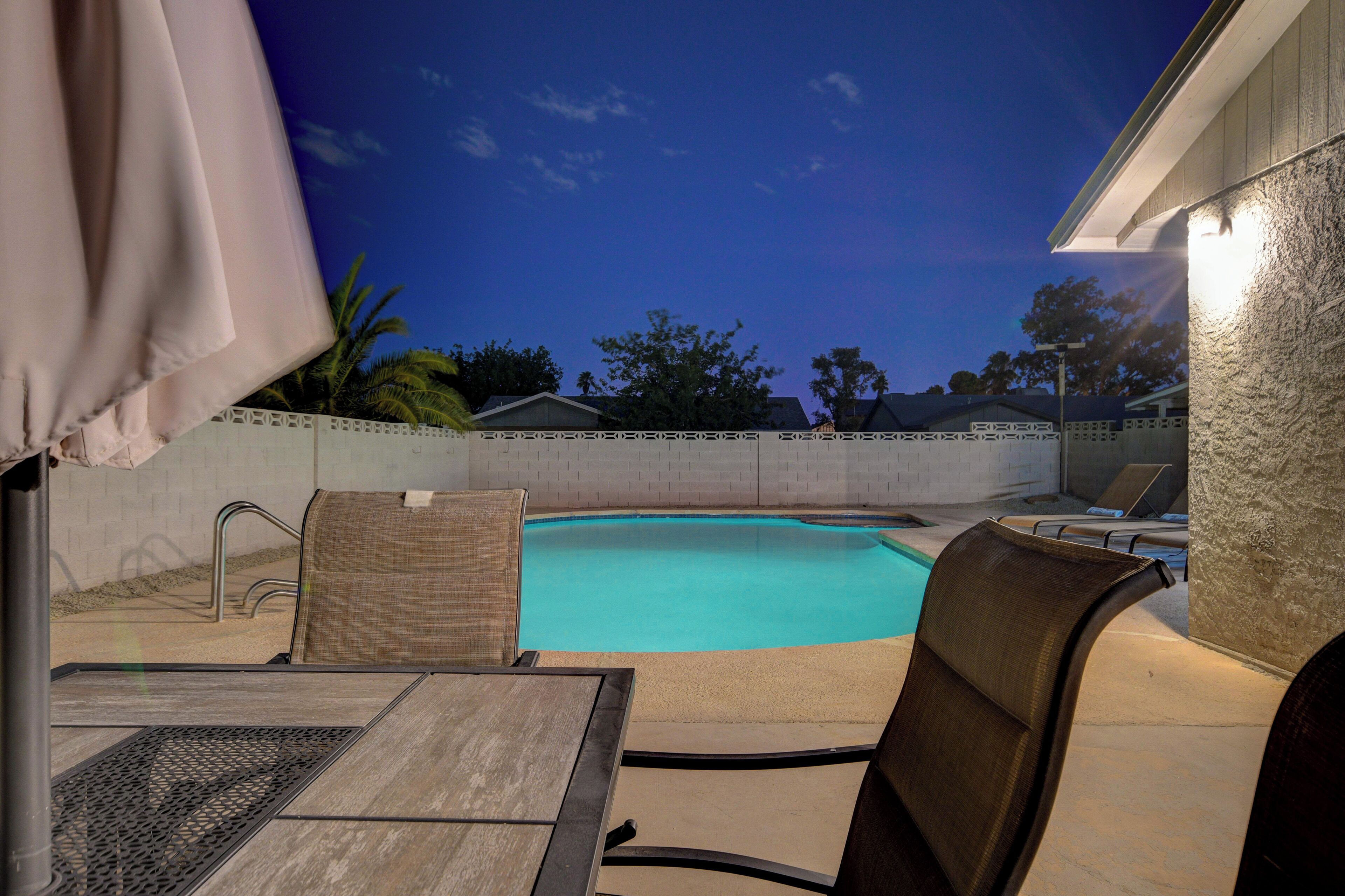 Un jardin avec une piscine, des chaises longues et une table.
