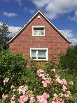 Une maison en briques rouges avec deux fenêtres et un toit triangulaire.