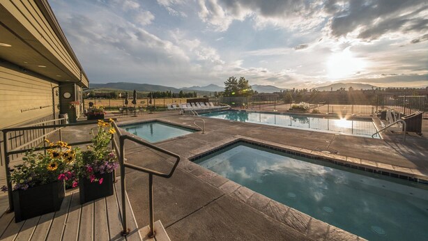 A pool area with two pools, surrounded by a deck with railings and flower planters. - Peaceful Fraser Condo Retreat, Close to Winter Park! (Fraser)
