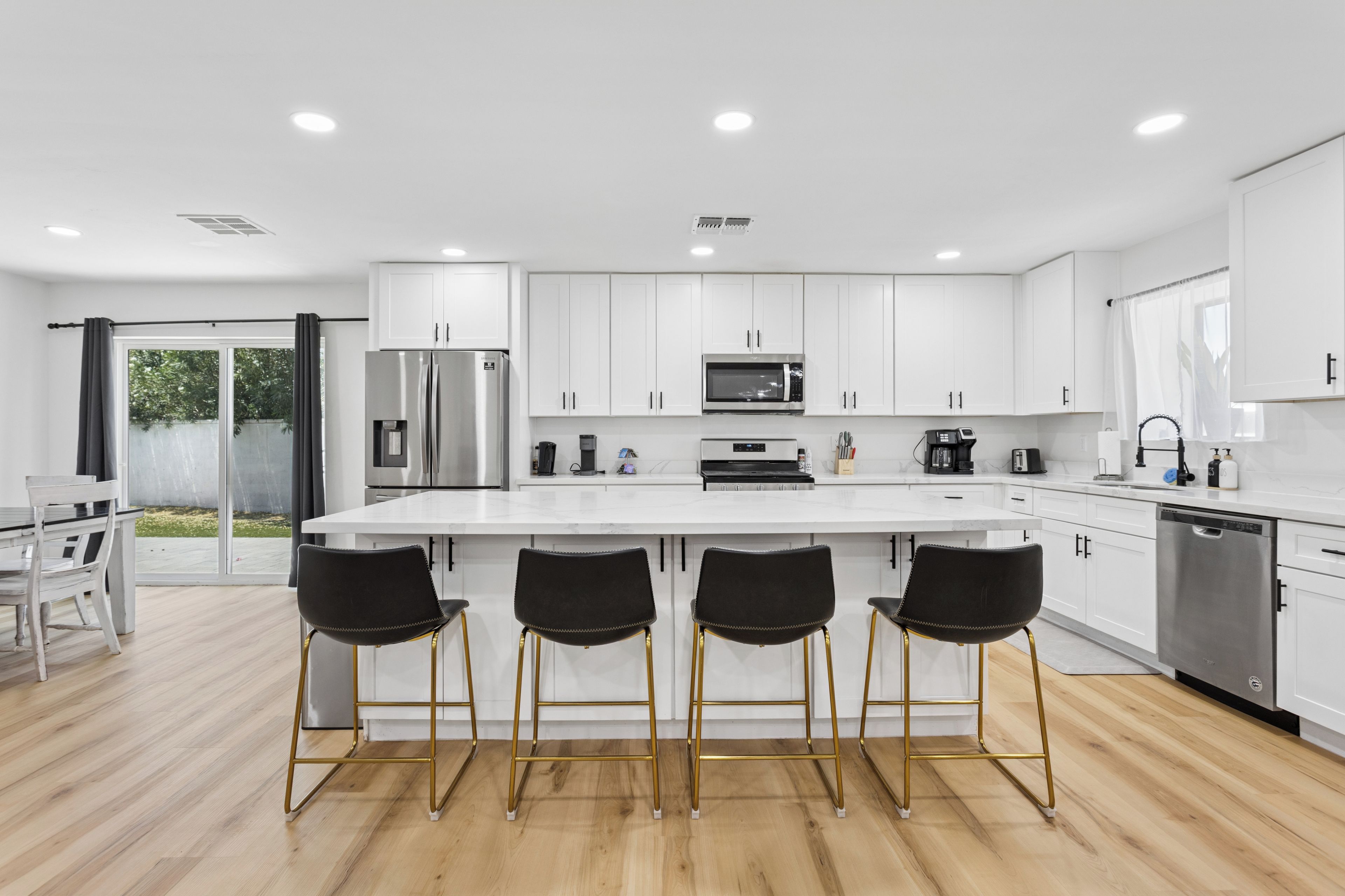 A modern kitchen with white cabinets, stainless steel appliances, and a central island with bar stools.