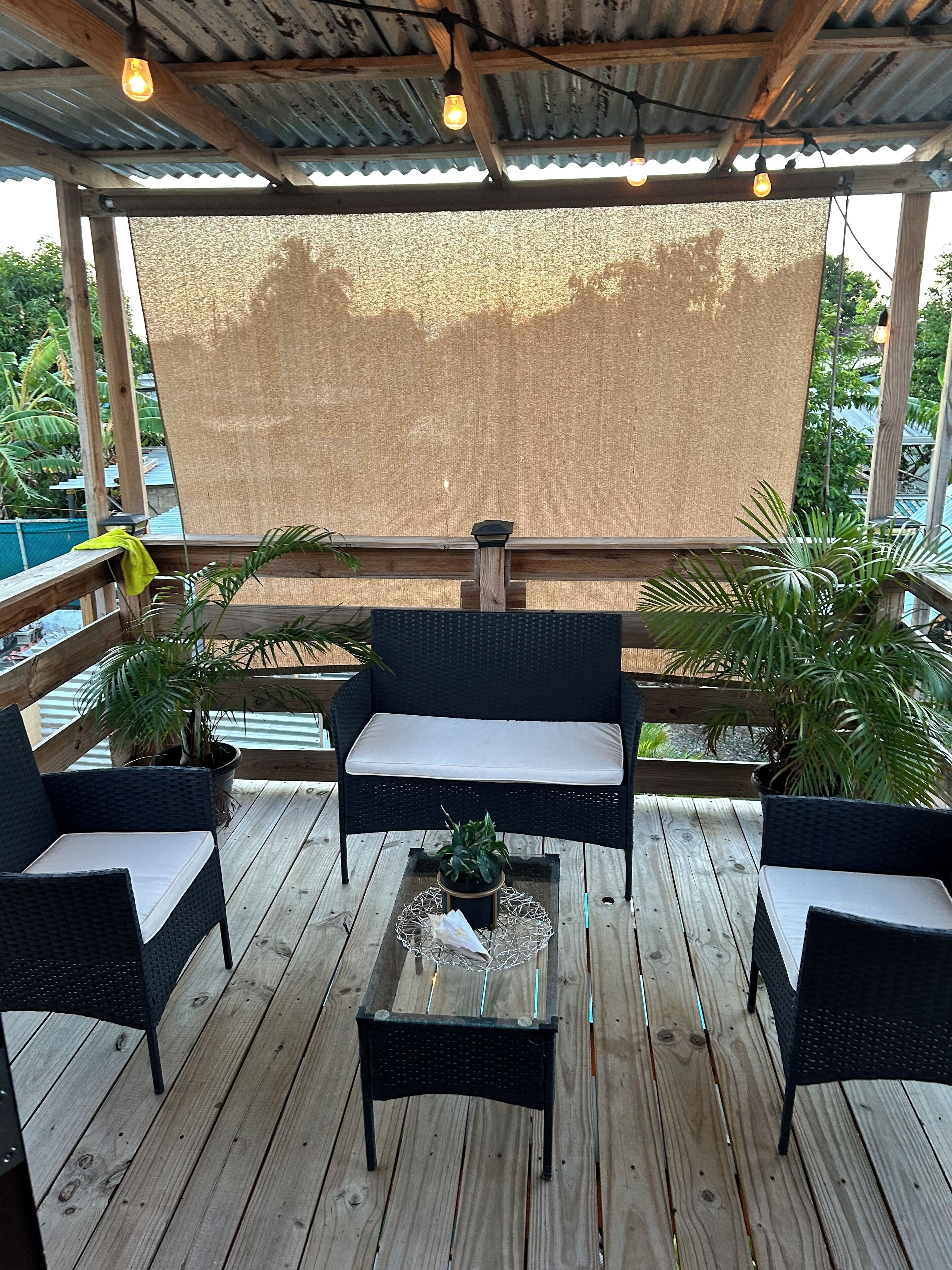An outdoor seating area with wicker furniture, a wooden table, and potted plants.