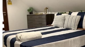A neatly made bed with striped bedding, a wooden headboard, and a bedside table with a lamp and a plant. - Villa ático beach house,pool,wifi,Netflix,backyard (Salinas)
