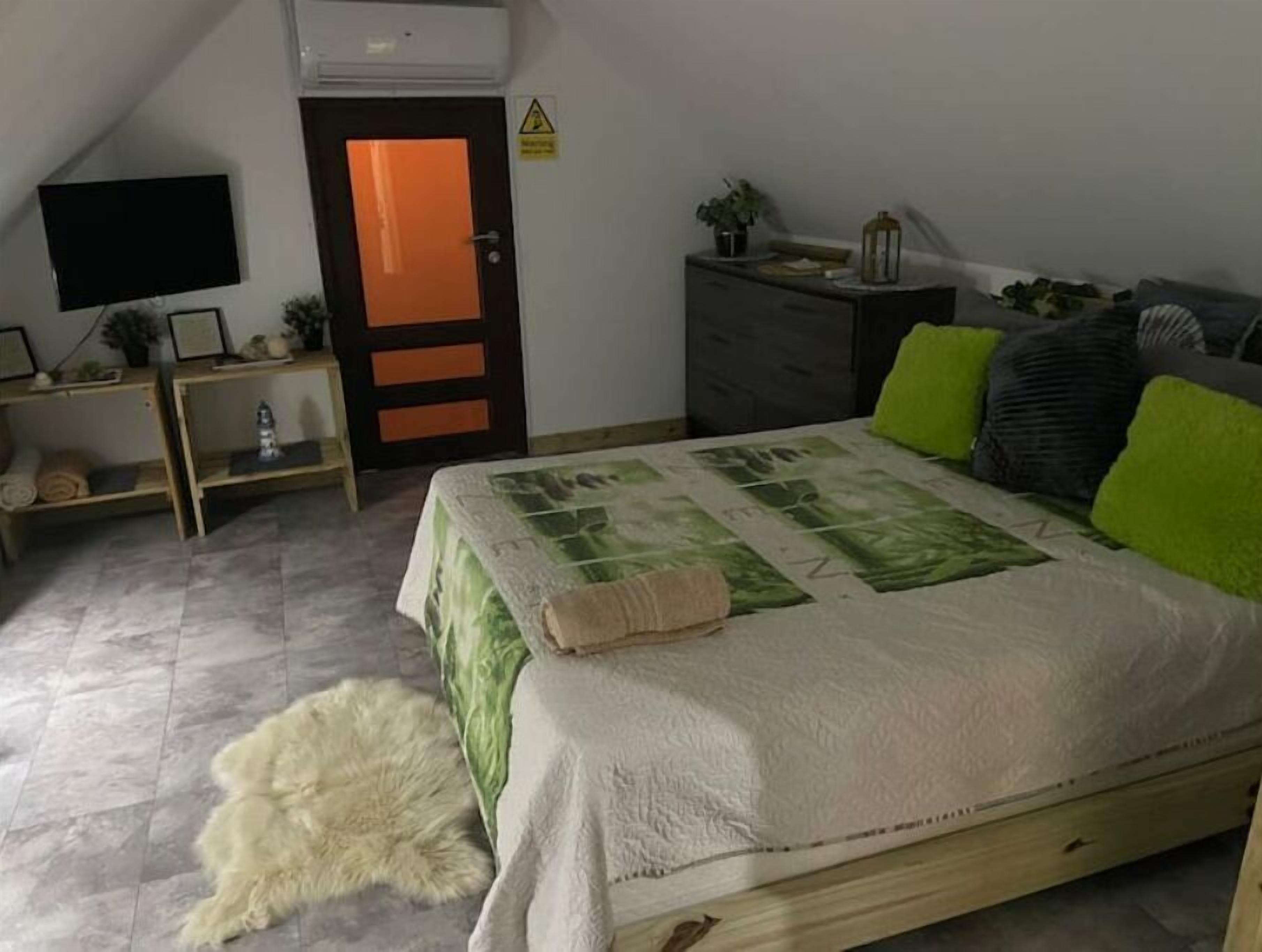 Ein Schlafzimmer mit Bett, Fernseher, Kleiderschrank, Schreibtisch und einer Tür.