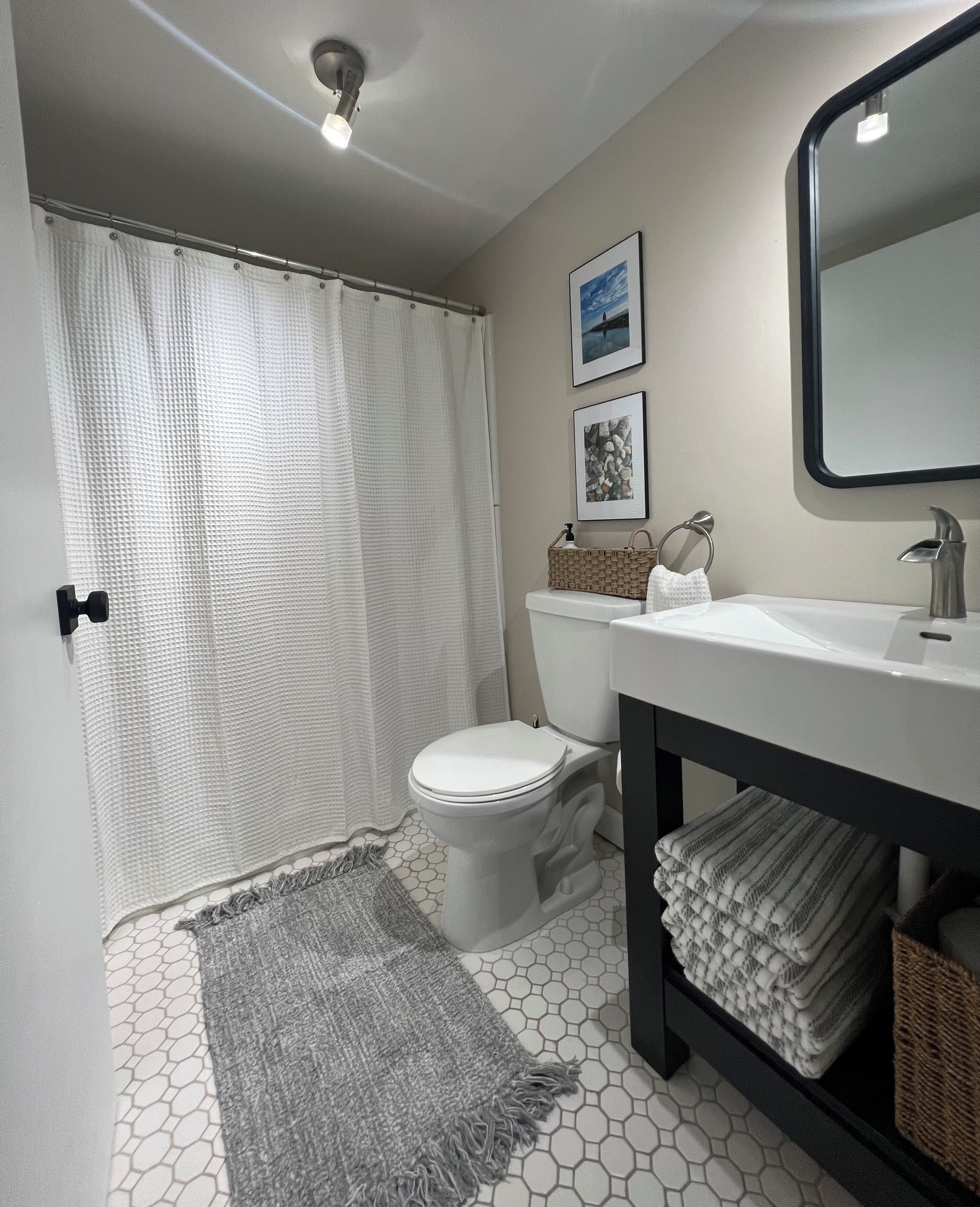 Un baño con inodoro, lavamanos y cortina de ducha.