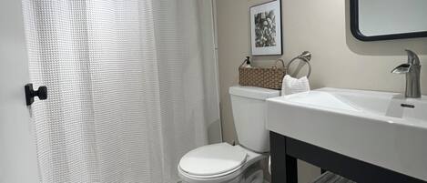 Un baño con inodoro, lavamanos y cortina de ducha.