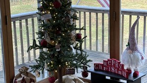 Une pièce chaleureuse, décorée d’un sapin de Noël, d’un gnome en peluche et d’une pancarte où l’on peut lire « Joyeux Noël ».