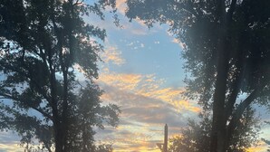 Auringonlaskunäkymä, jossa on laituri ja vene tyynellä järvellä, ja kaikkialla ympärillä puita.