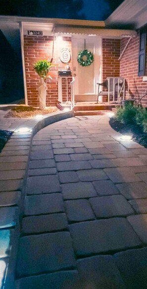 A brick building with a curved pathway leading to a door.