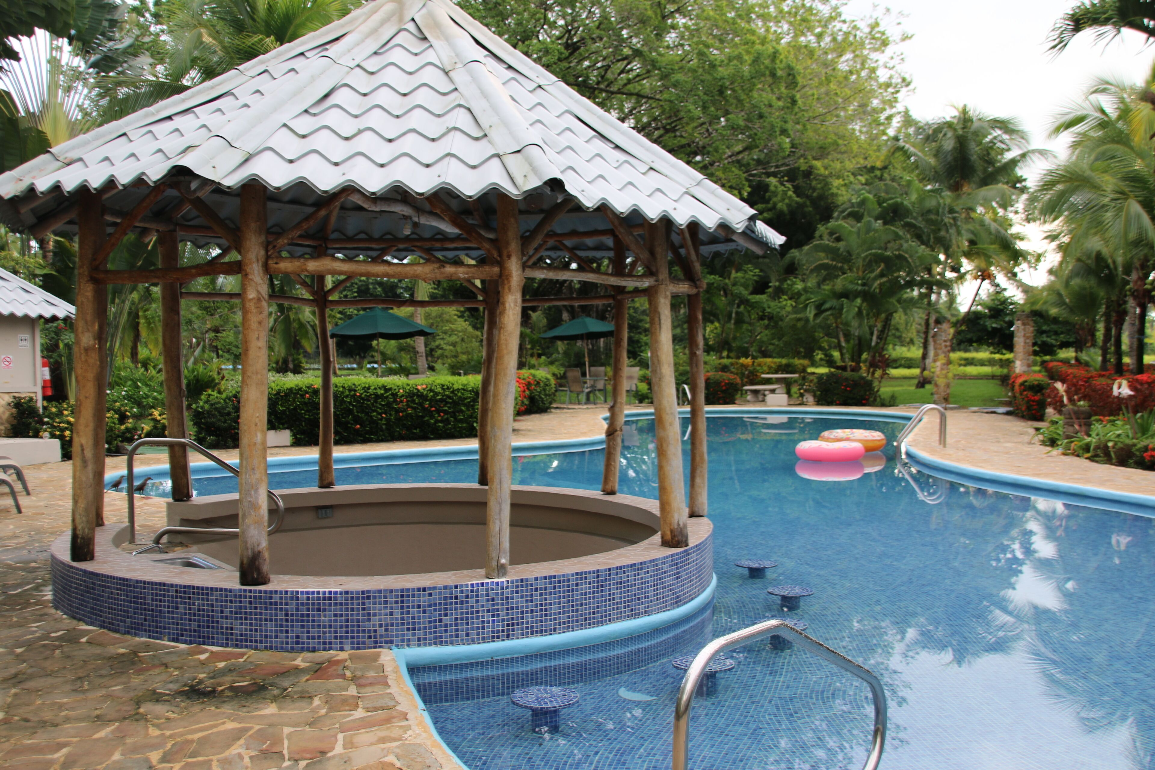 Un espace piscine agrémenté d’un gazebo, d’un jacuzzi et d’une petite piscine avec des bouées.