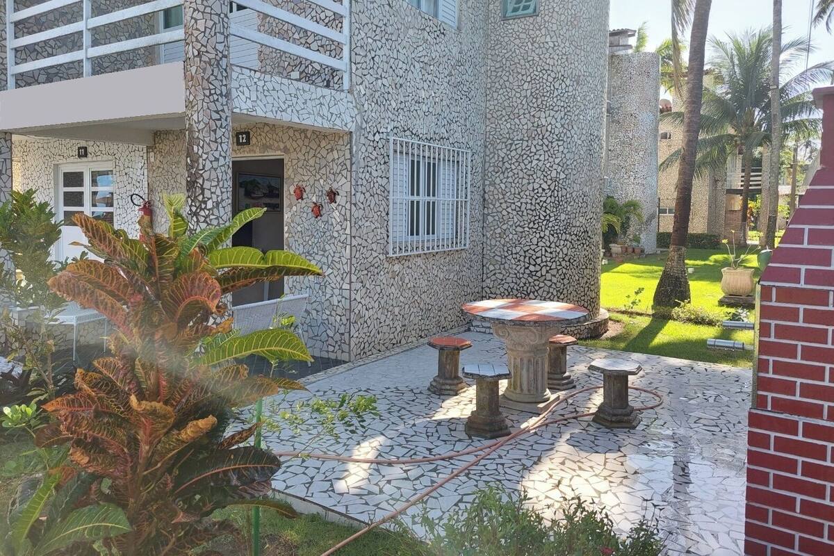 Un bâtiment dont la façade est ornée d’une mosaïque, doté d’un balcon et d’un patio aménagé avec une table et des chaises.