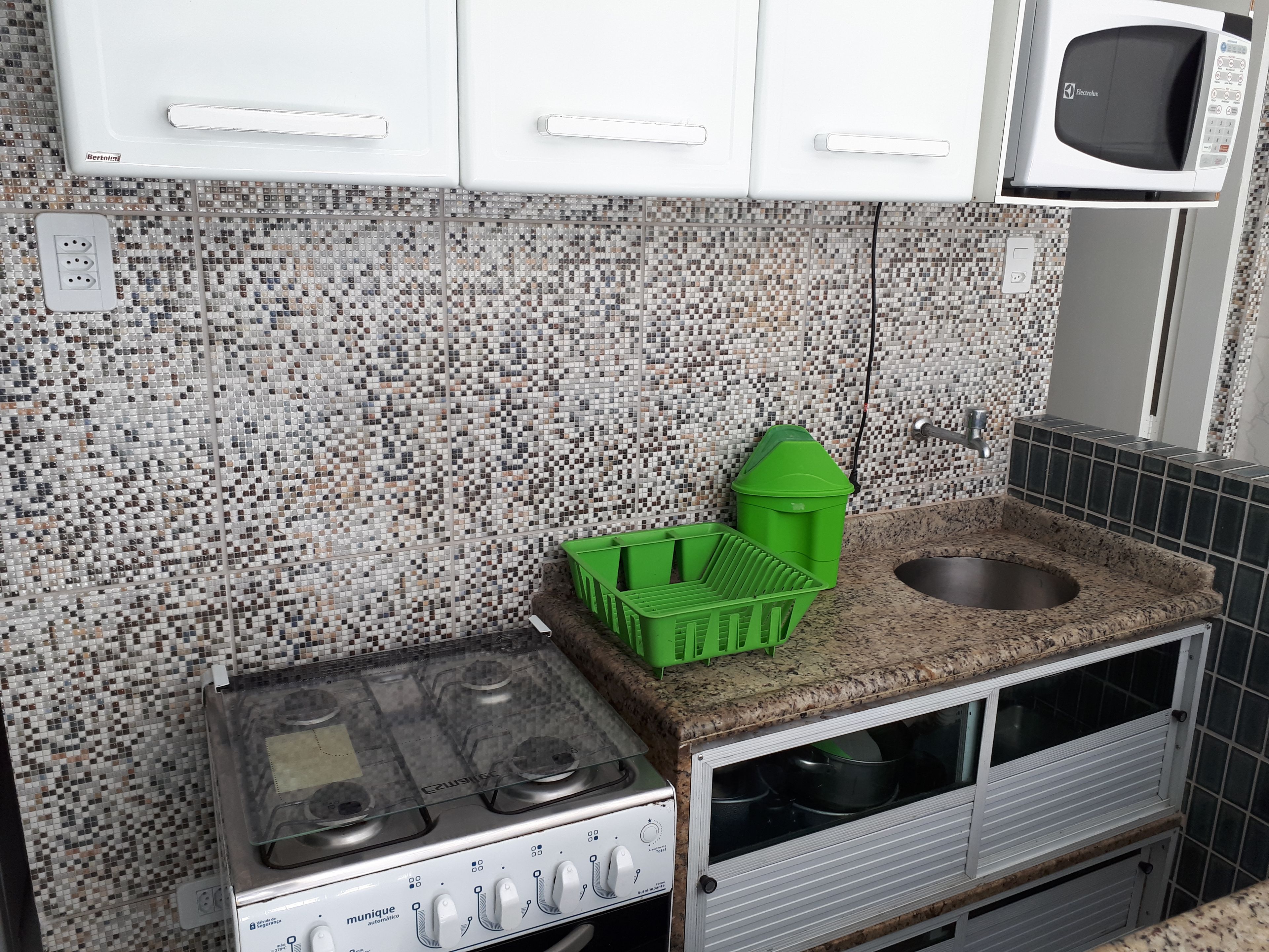 A kitchenette with a gas stove, a microwave, and a sink.