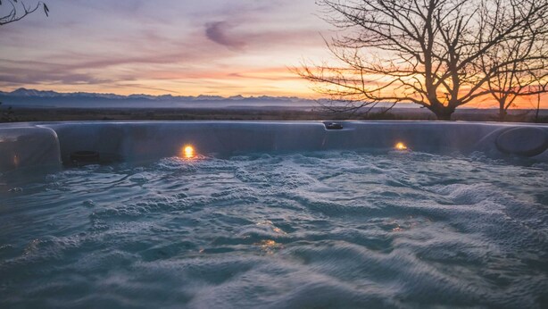 Un jacuzzi con vista al atardecer, rodeado de montañas.