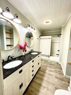 A bathroom with two sinks, a large mirror, and a shower area.