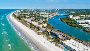 A coastal cityscape with a long sandy beach, a marina, and a mix of residential and commercial buildings.