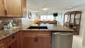 A kitchen with wooden cabinets, a stainless steel dishwasher, and a granite countertop.