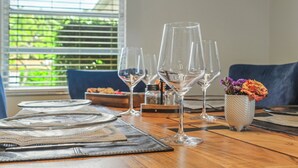Une table à manger dressée avec de la vaisselle en verre transparent, un petit vase avec des fleurs et une table en bois.
